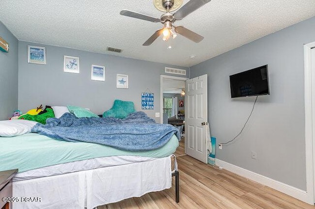 bedroom with a textured ceiling, hardwood / wood-style flooring, and ceiling fan