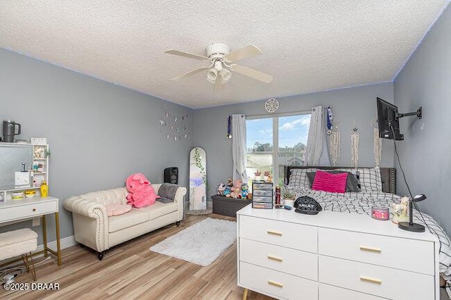 bedroom with a textured ceiling, light hardwood / wood-style floors, and ceiling fan