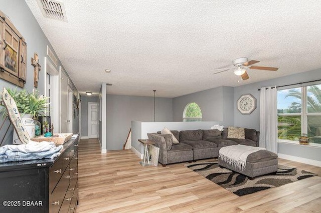 living room featuring a textured ceiling, light hardwood / wood-style floors, ceiling fan, and a healthy amount of sunlight