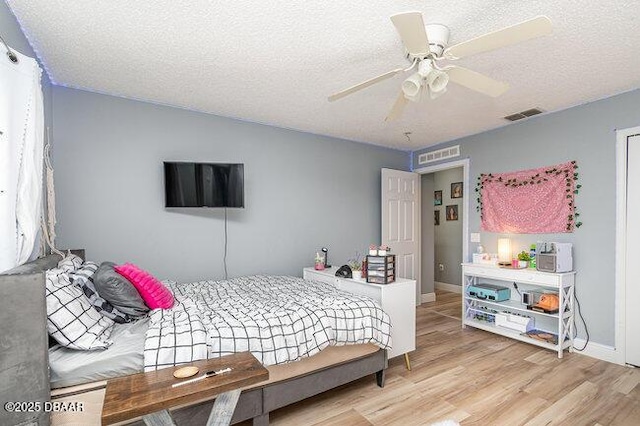 bedroom with ceiling fan, light hardwood / wood-style floors, and a textured ceiling