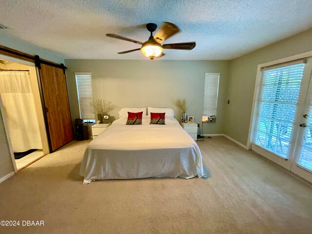 carpeted bedroom with a barn door, access to exterior, a textured ceiling, and ceiling fan