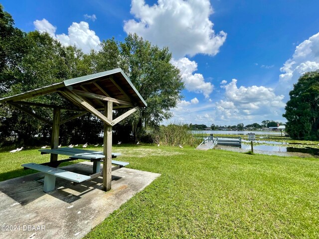 view of home's community with a water view, a dock, and a yard