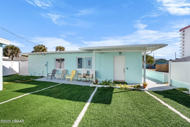 view of front facade with a front yard, fence, and a patio