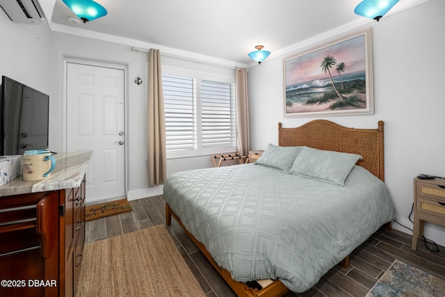 bedroom featuring a wall unit AC, baseboards, and wood finish floors