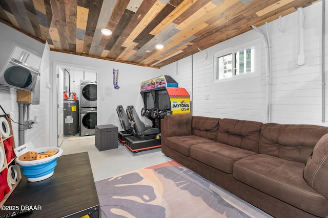 living room with stacked washer and dryer, finished concrete floors, wooden ceiling, and electric water heater