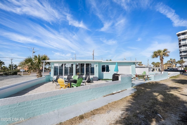 rear view of house featuring a garage, a patio, and a sunroom