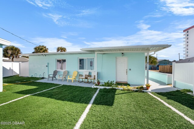 view of front of property featuring a patio area, fence, and a front yard