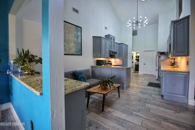 1948 Spruce Creek Lndg, Port Orange, FL 32128 - living area with high vaulted ceiling, light wood-style flooring, a chandelier, and visible vents