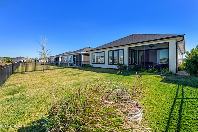 rear view of house featuring a yard, a sunroom, and ceiling fan