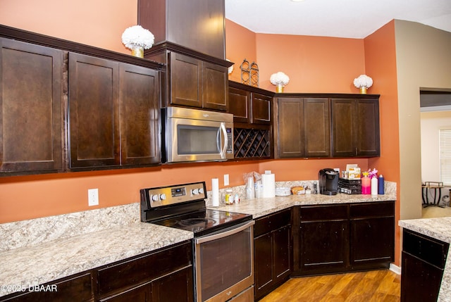 kitchen featuring appliances with stainless steel finishes, light wood-type flooring, and dark brown cabinetry