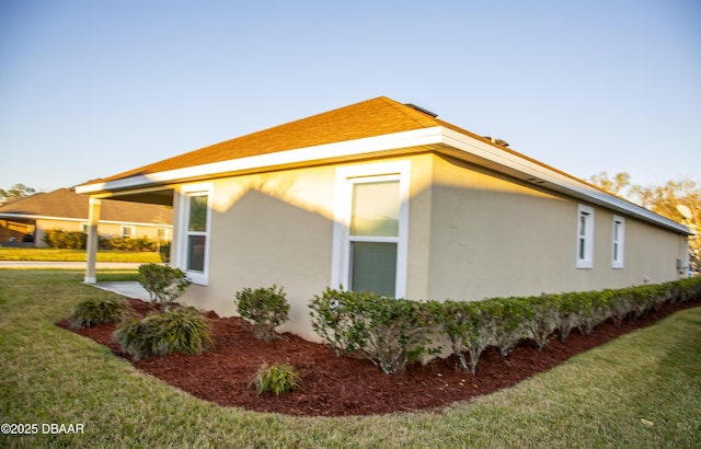 view of side of property featuring a lawn and stucco siding