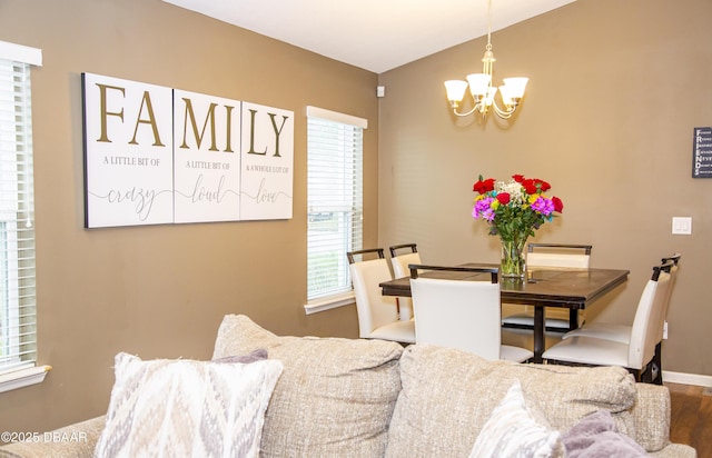 dining area with vaulted ceiling, baseboards, wood finished floors, and a notable chandelier