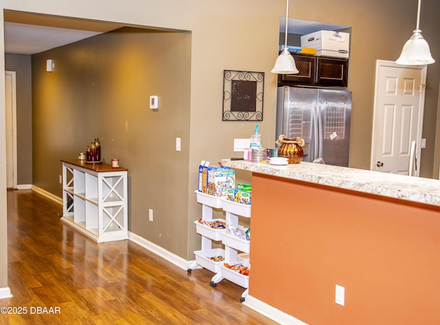 kitchen with light countertops, wood finished floors, stainless steel refrigerator, and baseboards