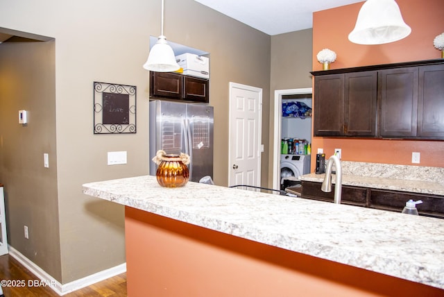 kitchen with pendant lighting, light countertops, dark brown cabinetry, and stainless steel refrigerator