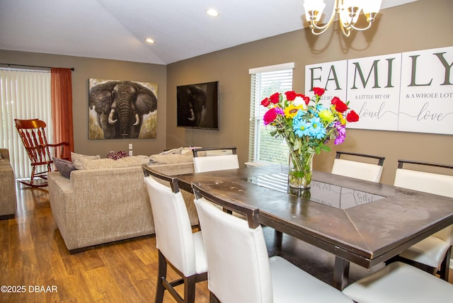 dining space with recessed lighting, a notable chandelier, vaulted ceiling, and wood finished floors