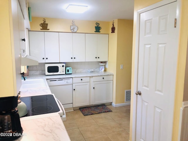 kitchen with white cabinets, white appliances, light tile patterned flooring, and backsplash