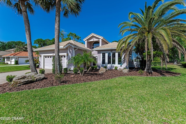 view of front of home with an attached garage, stucco siding, a front yard, a tiled roof, and driveway