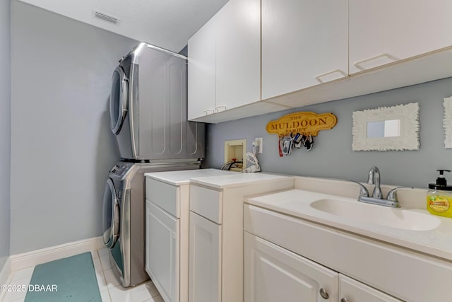 laundry area featuring visible vents, cabinet space, a sink, baseboards, and stacked washer and clothes dryer