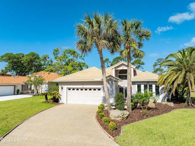 view of front of house featuring a tiled roof, a front yard, a garage, decorative driveway, and stucco siding