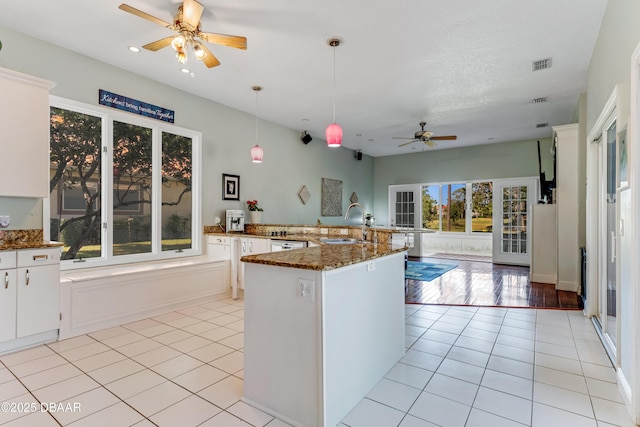 kitchen with a ceiling fan, visible vents, hanging light fixtures, a sink, and a peninsula