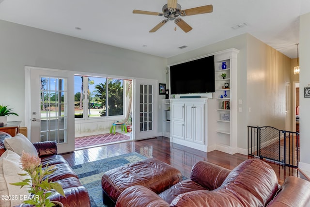 living area with built in shelves, a ceiling fan, baseboards, wood finished floors, and visible vents