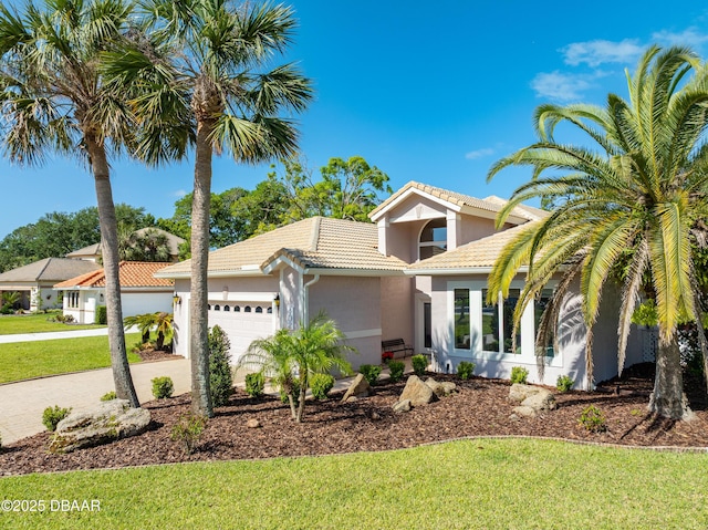 mediterranean / spanish-style house with an attached garage, a front lawn, a tile roof, stucco siding, and driveway