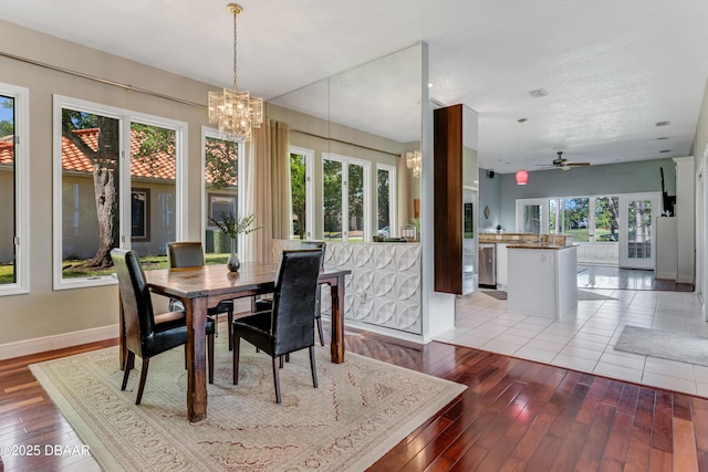 dining area with baseboards, light wood finished floors, and ceiling fan with notable chandelier