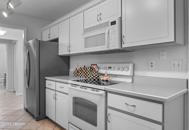 kitchen featuring white cabinetry, light tile patterned floors, and white appliances