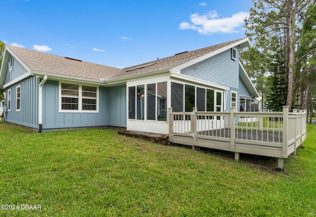 back of house featuring a deck, a lawn, and a sunroom