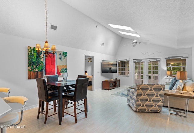 dining area featuring french doors, ceiling fan with notable chandelier, light wood-type flooring, and a skylight