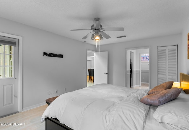 bedroom with a textured ceiling, light wood-type flooring, ceiling fan, and ensuite bathroom