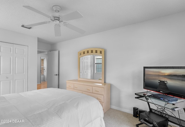 bedroom featuring a closet, a textured ceiling, light colored carpet, and ceiling fan