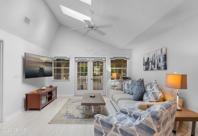 living room with french doors, high vaulted ceiling, light hardwood / wood-style floors, a skylight, and ceiling fan