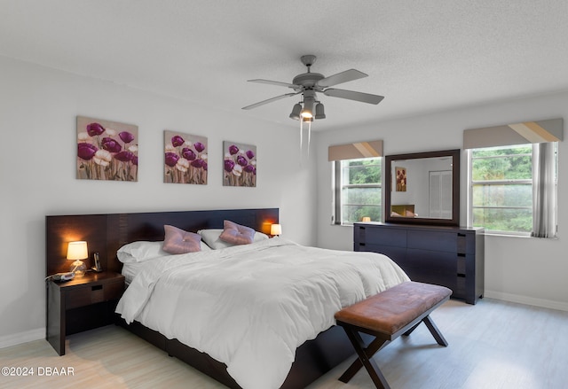 bedroom with a textured ceiling, light hardwood / wood-style flooring, and ceiling fan