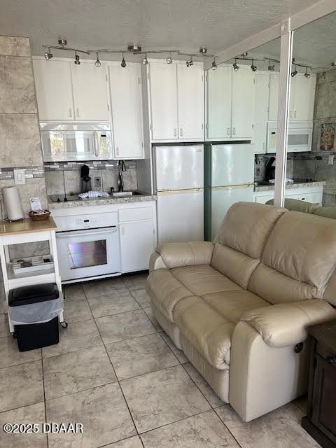 453 S Atlantic Ave, Ormond Beach, FL 32176 - kitchen featuring white appliances, track lighting, white cabinets, and open floor plan