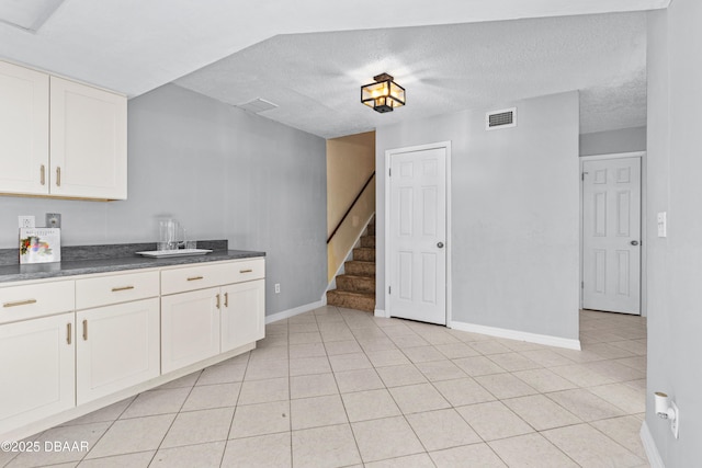 kitchen featuring white cabinetry, light tile patterned floors, and a textured ceiling