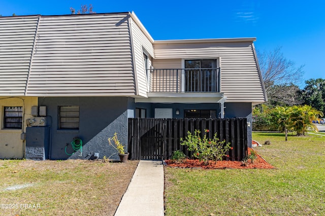 view of front of house with a front lawn and a balcony