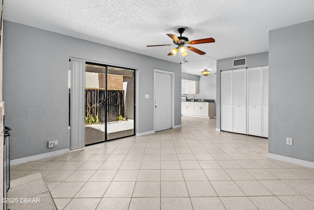 unfurnished room featuring ceiling fan, light tile patterned floors, and a textured ceiling