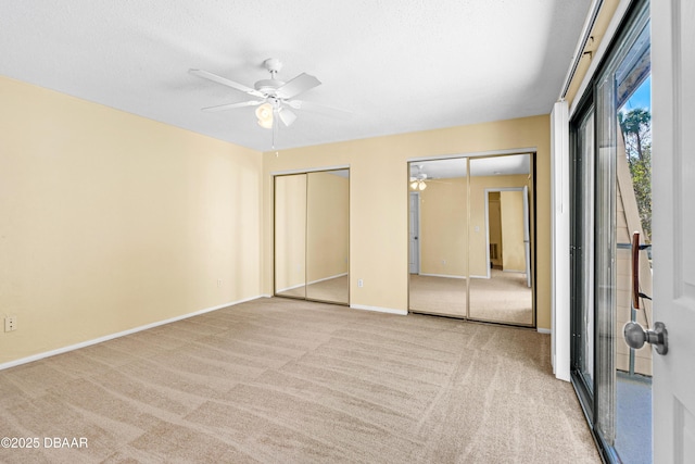 unfurnished bedroom with ceiling fan, two closets, light colored carpet, and a textured ceiling