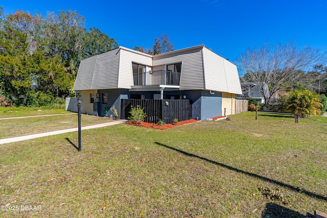 rear view of property featuring a balcony and a lawn