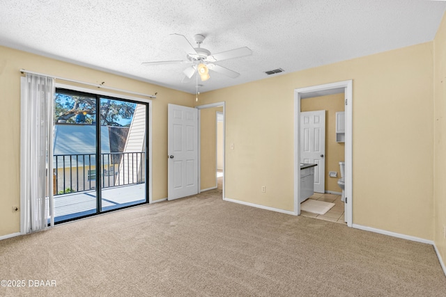 unfurnished bedroom featuring ceiling fan, light colored carpet, access to outside, and ensuite bath