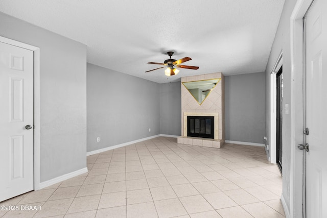 unfurnished living room with ceiling fan, a textured ceiling, light tile patterned floors, and a fireplace