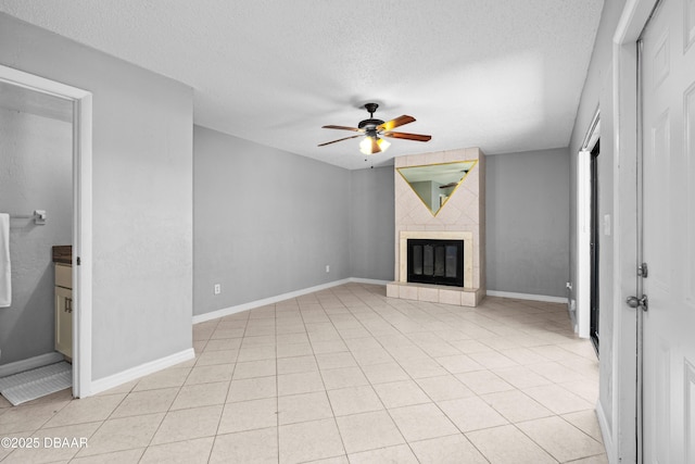 unfurnished living room featuring a textured ceiling, ceiling fan, light tile patterned flooring, and a tile fireplace