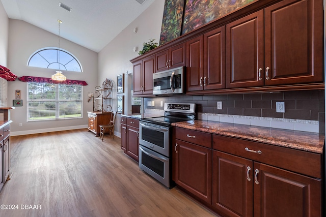 kitchen featuring high vaulted ceiling, stainless steel appliances, tasteful backsplash, and light hardwood / wood-style flooring