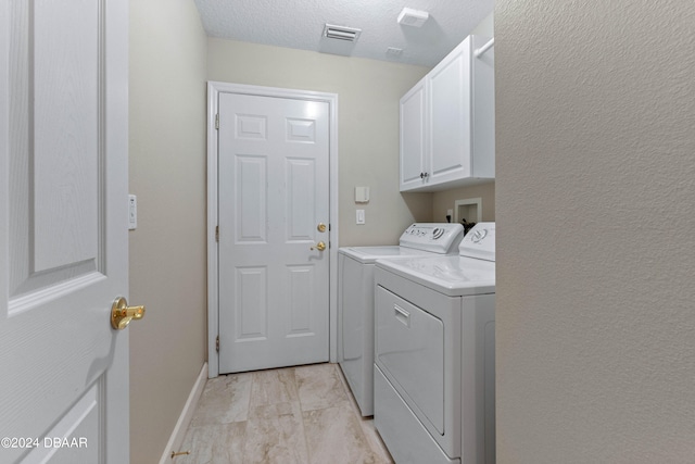 laundry area featuring cabinets, washing machine and dryer, and a textured ceiling