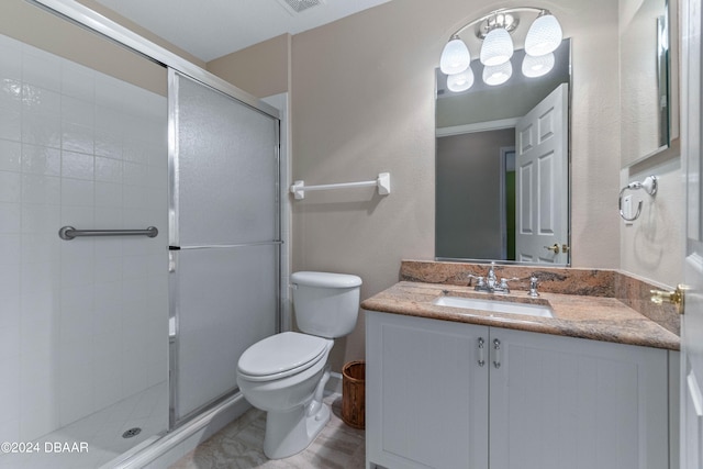 bathroom with a shower with shower door, vanity, and toilet