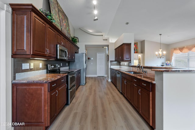 kitchen featuring stainless steel appliances, light wood-type flooring, a notable chandelier, pendant lighting, and sink