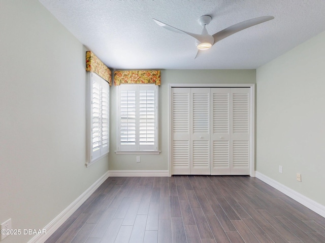 unfurnished bedroom with a textured ceiling, a closet, dark wood finished floors, and baseboards