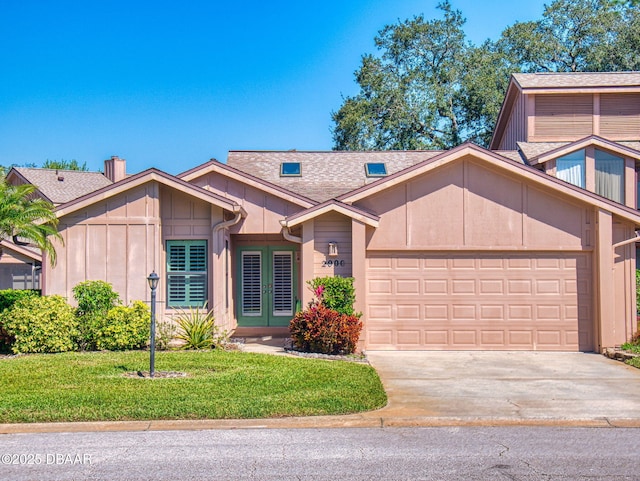 view of front facade featuring a garage, french doors, a front lawn, and concrete driveway