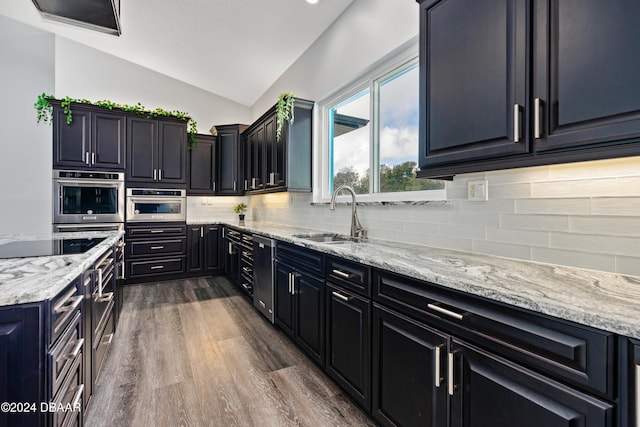 kitchen featuring sink, dark wood-type flooring, light stone counters, lofted ceiling, and decorative backsplash